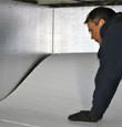 A contractor installing TerraBlock™ floor insulation in a Bryant crawl space