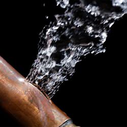 A bursting copper pipe in Sherwood, with water gushing out.