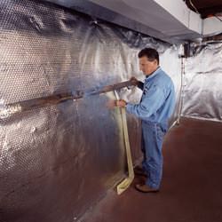 Installation of a radiant heat and vapor barrier on a basement wall in College Station