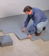 Contractors installing basement subfloor tiles and matting on a concrete basement floor in Maumelle, Arkansas
