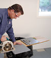 installing a waterproof vapor barrier on a basement floor to prepare for basement carpeting in a Sherwood home